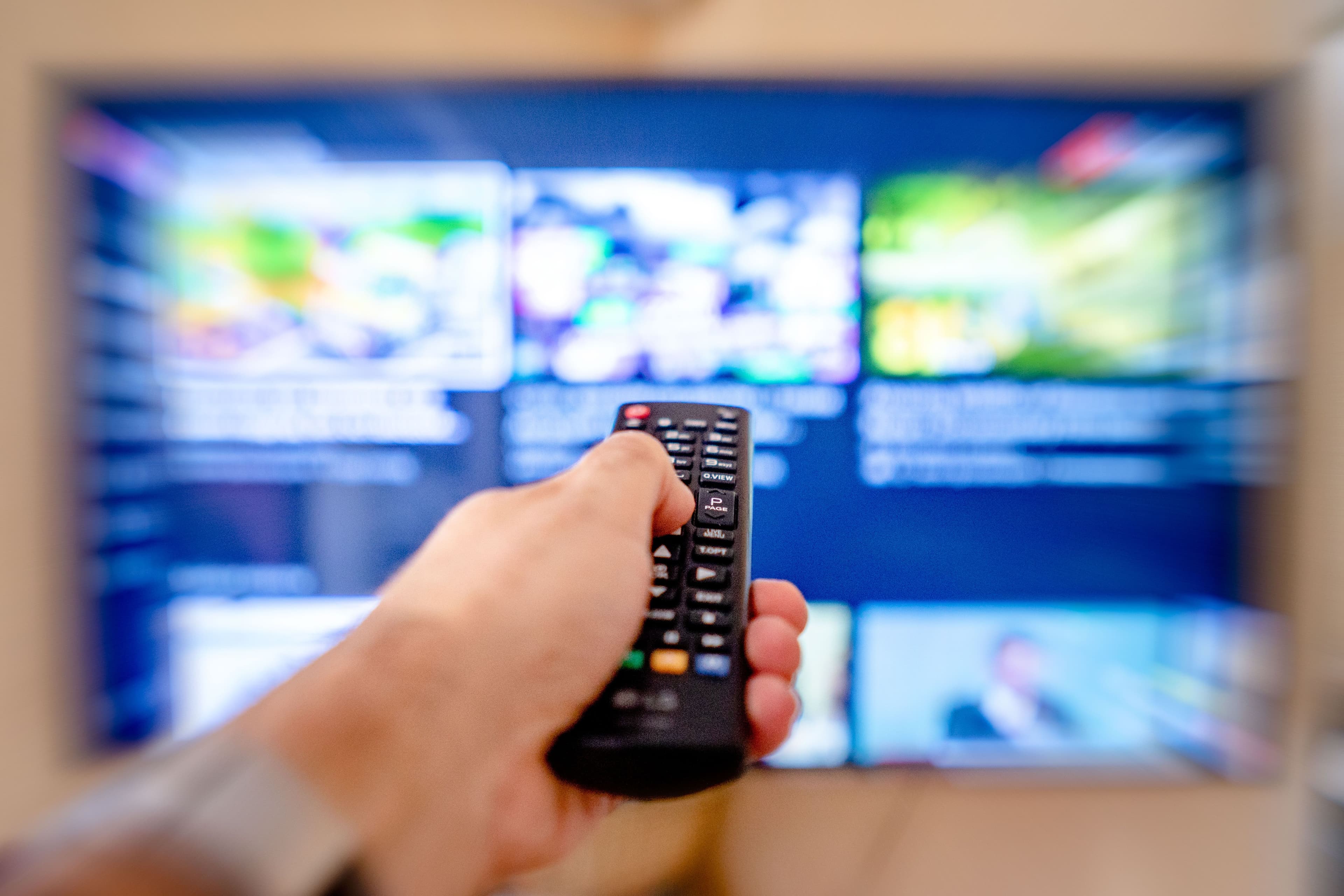 Person using a remote control to browse a premium streaming interface on a smart TV